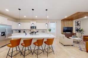 Enjoy cooking in this kitchen with a central island, bar stools, microwave, and stainless steel refrigerator.
