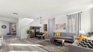 A modern living room with a sofa, coffee table, and a dining area with a table and chairs. - World Showcase 5 Bedrooms at Windwood Bay (Davenport)