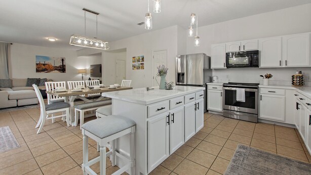 A modern kitchen with white cabinets, stainless steel appliances, and a central island. - World Showcase 5 Bedrooms at Windwood Bay (Davenport)