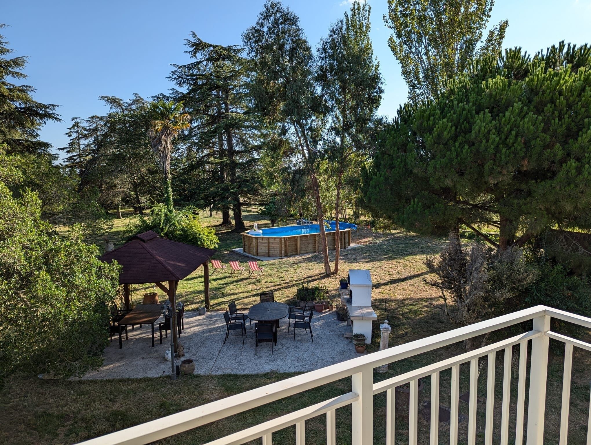 Ein Garten mit Whirlpool, Terrassenmöbeln und einem überdachten Sitzbereich.