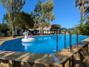 A swimming pool with a unicorn float, surrounded by trees and a wooden deck. - Villa Louisiane - Maison avec piscine (Port-Sainte-Marie)