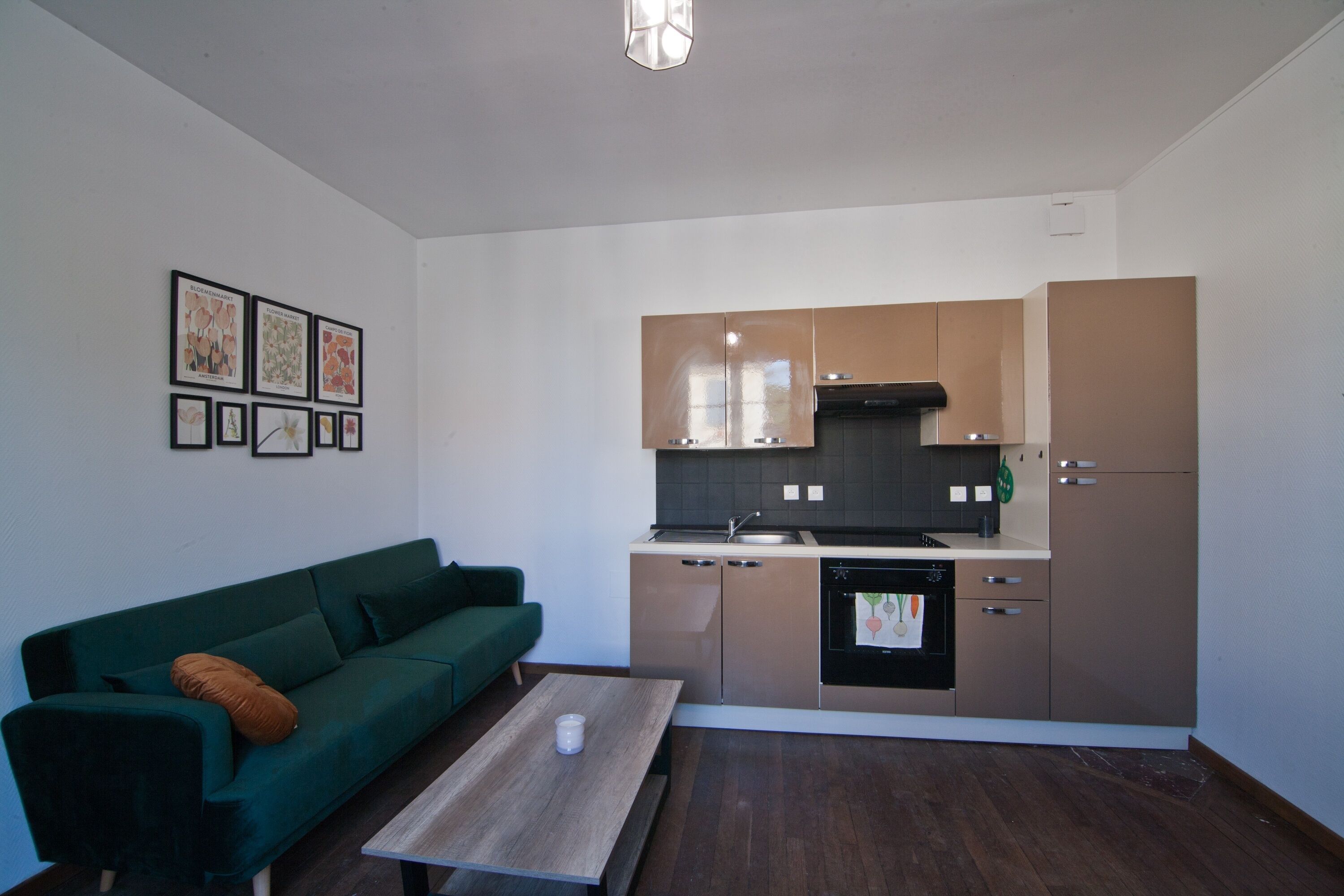 Una cocina compacta con electrodomésticos modernos, un sofá verde y una mesa de centro de madera.