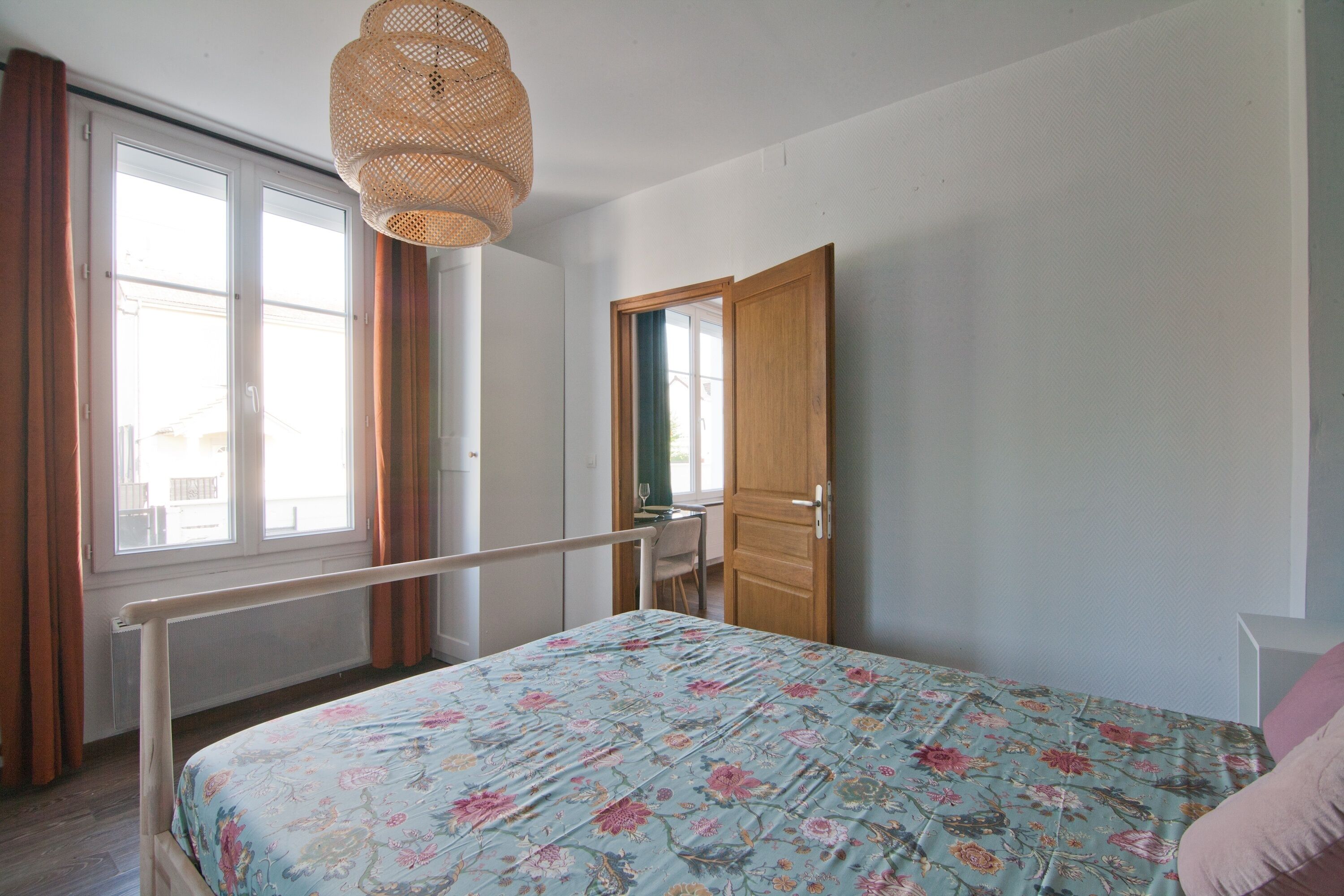 Une chambre à coucher avec un lit, une fenêtre, une porte et un luminaire suspendu.