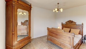 Ein Schlafzimmer mit einem hölzernen Bett, einem großen Spiegel und einer Chandelüstere.