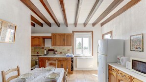 Eine Küche mit Holzausstattung, einem Esstisch mit Tellern und Gläsern, einem Kühlschrank und einer Mikrowelle.