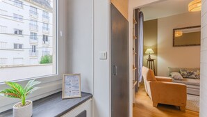 A modern apartment with a view of a building, a potted plant, a framed menu, and a sofa. - Ernest - appt calme, proche centre de nantes (Nantes)