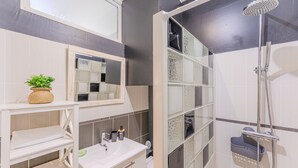 A bathroom with a shower, a sink, a mirror, and a shelf with a plant. - Ernest - appt calme, proche centre de nantes (Nantes)