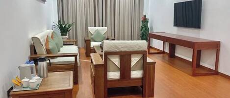 A modern living room with a sofa, armchairs, a coffee table, a TV, and a dining table.