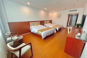 Habitación de hotel con dos camas, un escritorio con silla, una mesita con un plato de comida y un dispensador de agua.