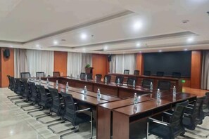 Una sala conferenze con un lungo tavolo, diverse sedie e uno schermo di proiezione.