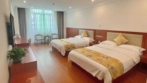 Ein Hotelzimmer mit zwei Betten, einem Schreibtisch, einem Stuhl und einem Fernseher.