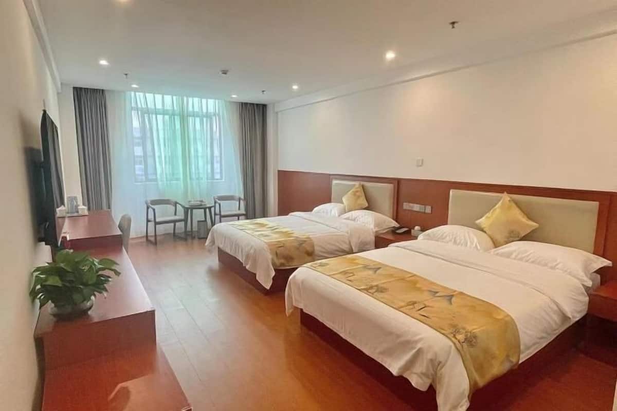 Une chambre d’hôtel avec deux lits, un bureau, une chaise et un téléviseur.