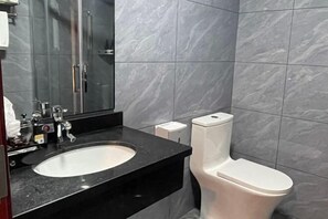 Un baño moderno con encimera negra, lavabo blanco y retrete.