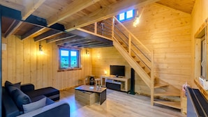 A wooden interior with a staircase, a sofa, a coffee table, and a television.