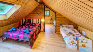 A cozy attic bedroom with a sloped ceiling, a skylight, a heart-shaped decoration, and two beds with colorful bedding.