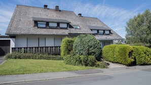 A two-story house with a sloped roof, a garage, and a well-maintained lawn.