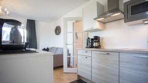A modern kitchen with white cabinetry, a coffee maker, and a microwave.