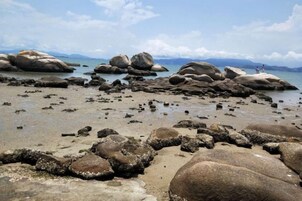 Una playa rocosa con grandes rocas y agua tranquila.