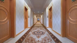 A long, narrow hallway with wooden doors on either side, each marked with a number. - Vienna International Hotel (Zijin)