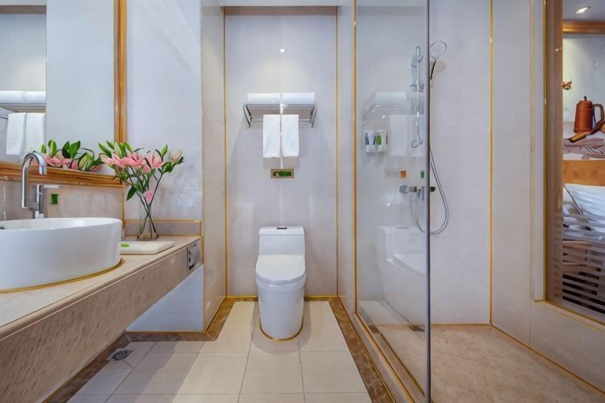 A modern bathroom with a large sink, toilet, and glass-enclosed shower.