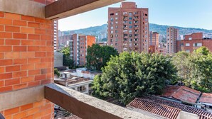 Vista desde un balcón sobre un paisaje urbano con edificios altos, árboles y cielo despejado.