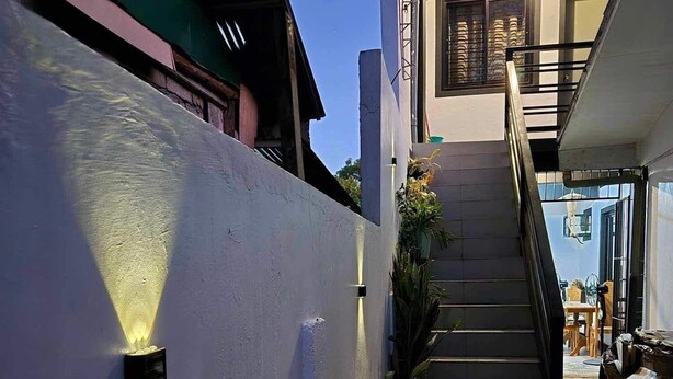 Un  étroit couloir extérieur avec un escalier menant à un palier situé au deuxième étage.
