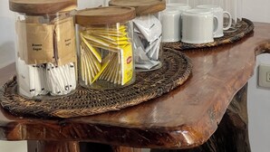 Une table en bois sur laquelle sont posés des pots de sucre et des sachets de crème liquide.