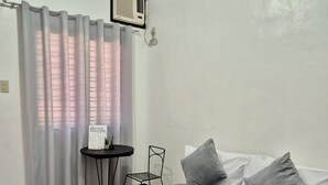 Une chambre d’hôtel avec un lit, une petite table, une chaise et une fenêtre avec des rideaux.