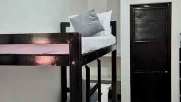 Een slaapkamer met stapelbedden, een zwarte deur en een kleed op de vloer.