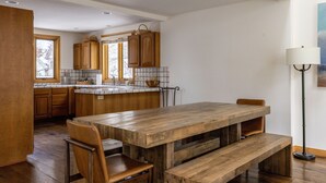 Une cuisine spacieuse avec des meubles de rangement en bois, une grande table à manger en bois et un banc.