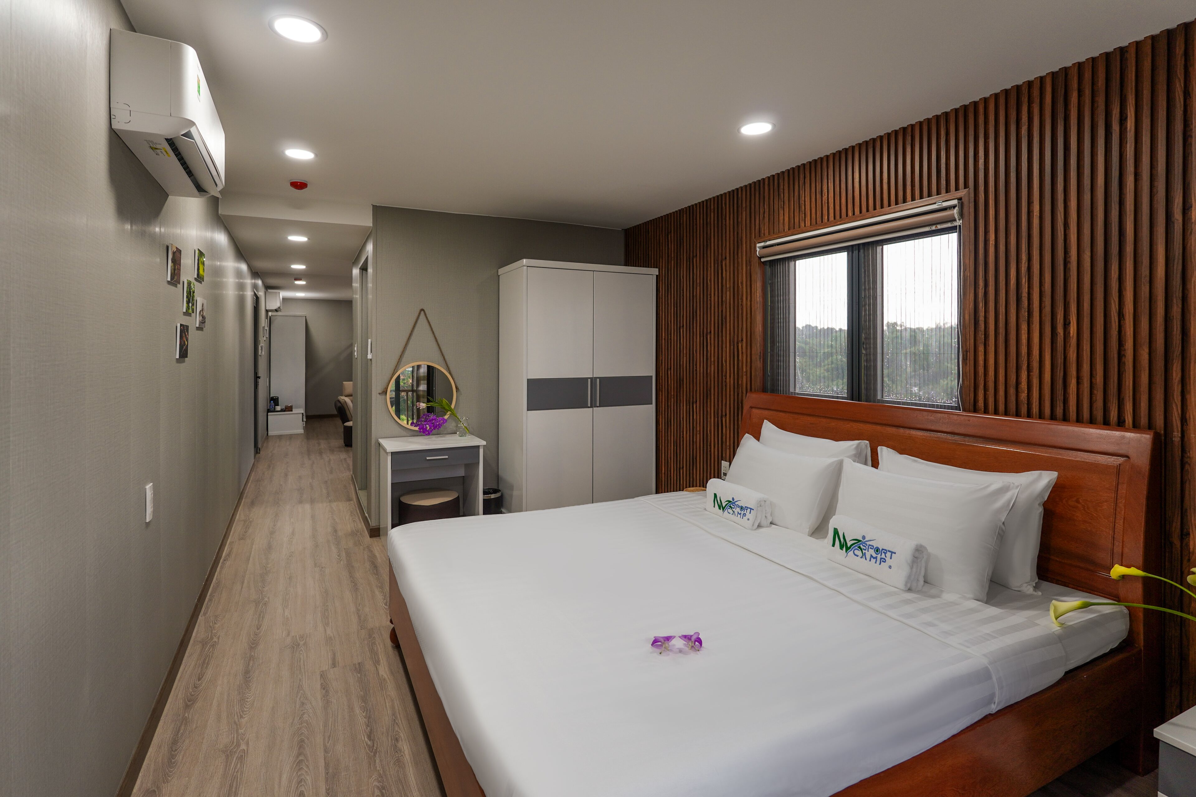 Una habitación de hotel con cabecera de madera, una cama grande, un escritorio y un armario.