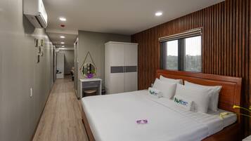 Una habitación de hotel con cabecera de madera, una cama grande, un escritorio y un armario.