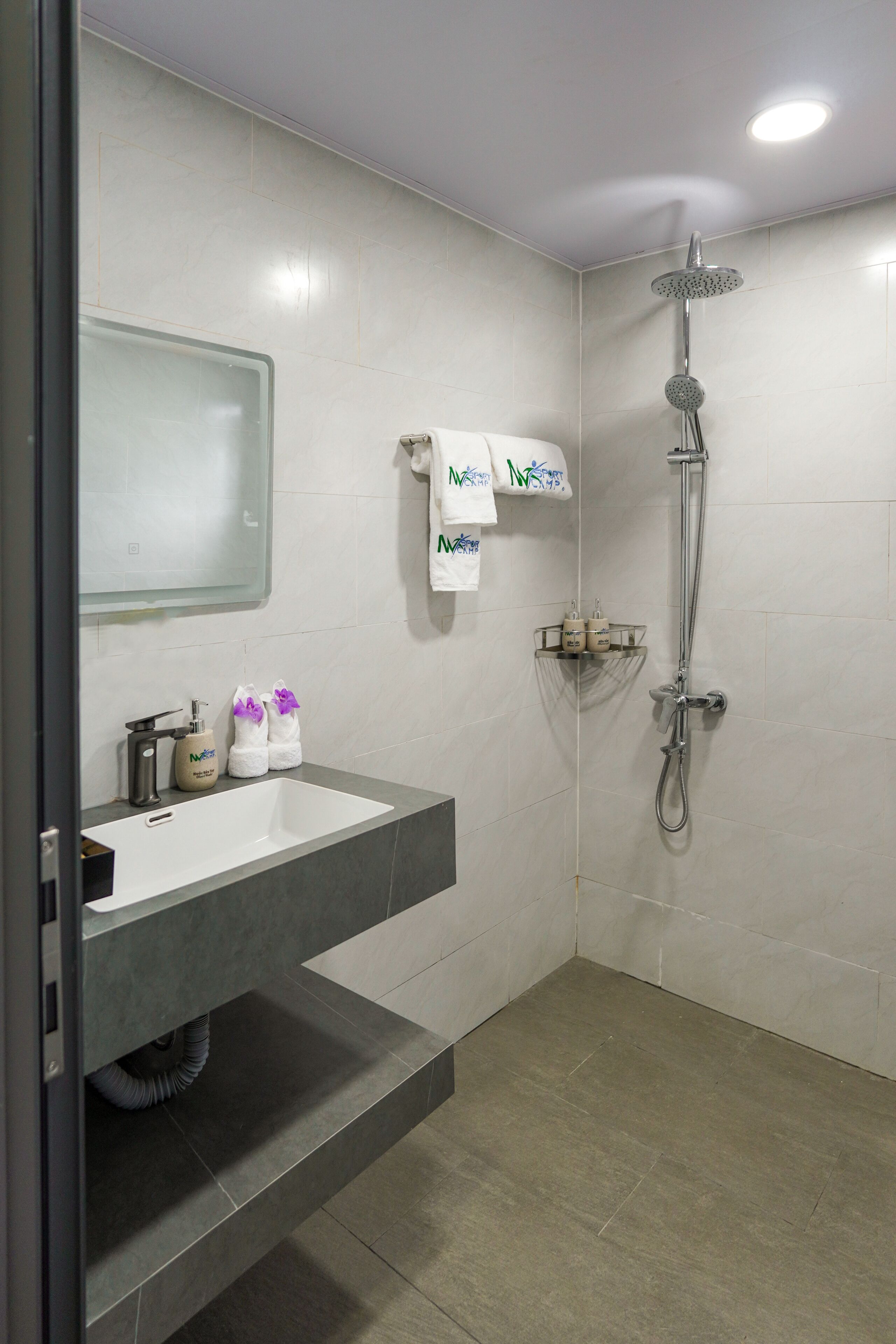 A modern bathroom with a white sink, a mirror, a shower, and a towel rack.
