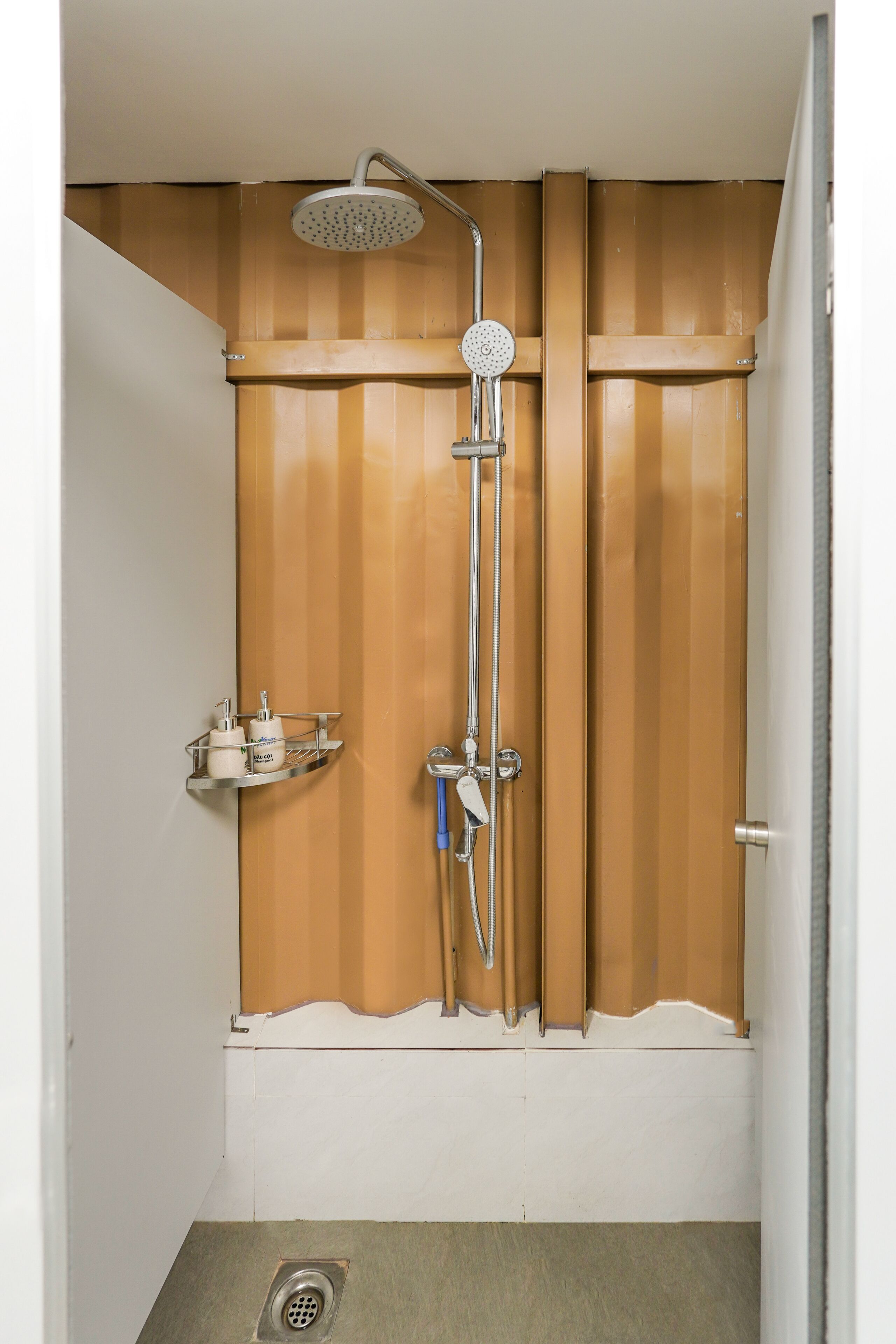 A shower with a handheld showerhead and a wall-mounted faucet.