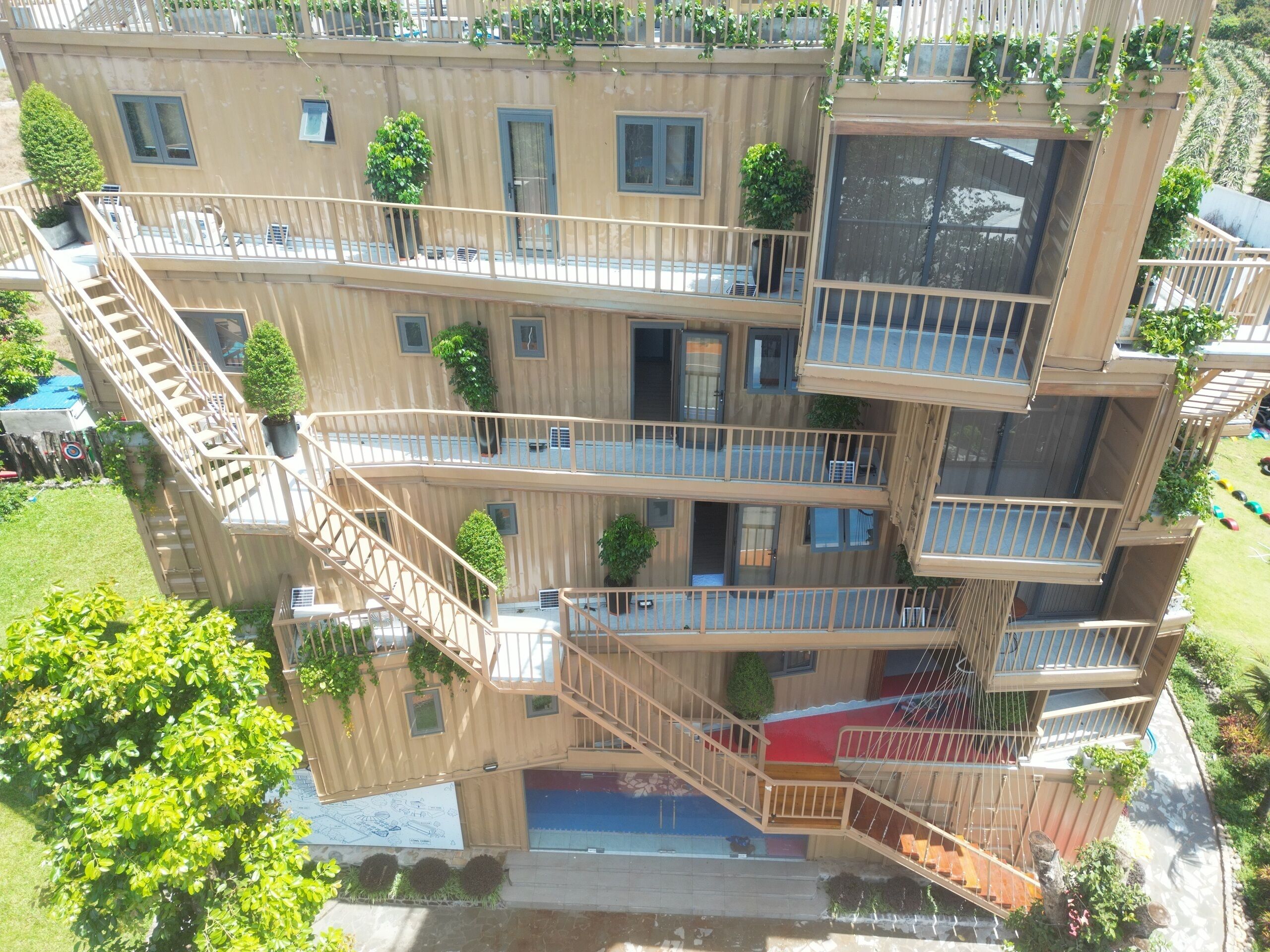 Un edificio de varios pisos con balcones, escaleras y plantas en macetas.