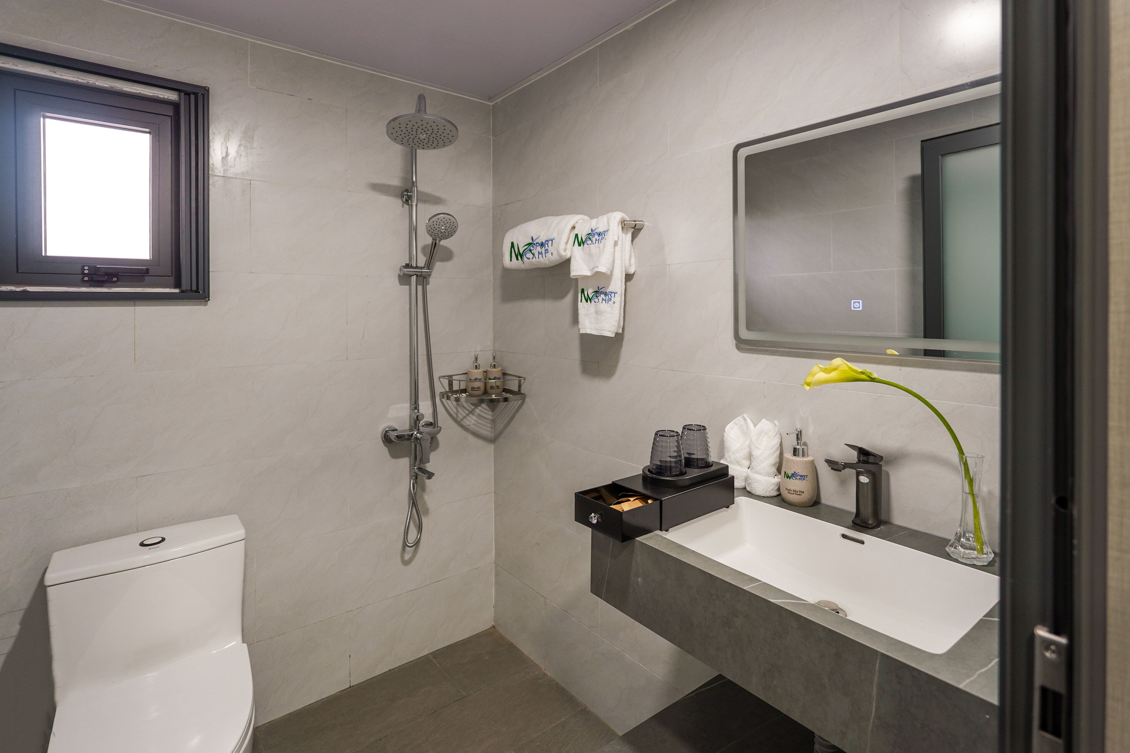 A modern bathroom with a toilet, shower, sink, and a mirror.