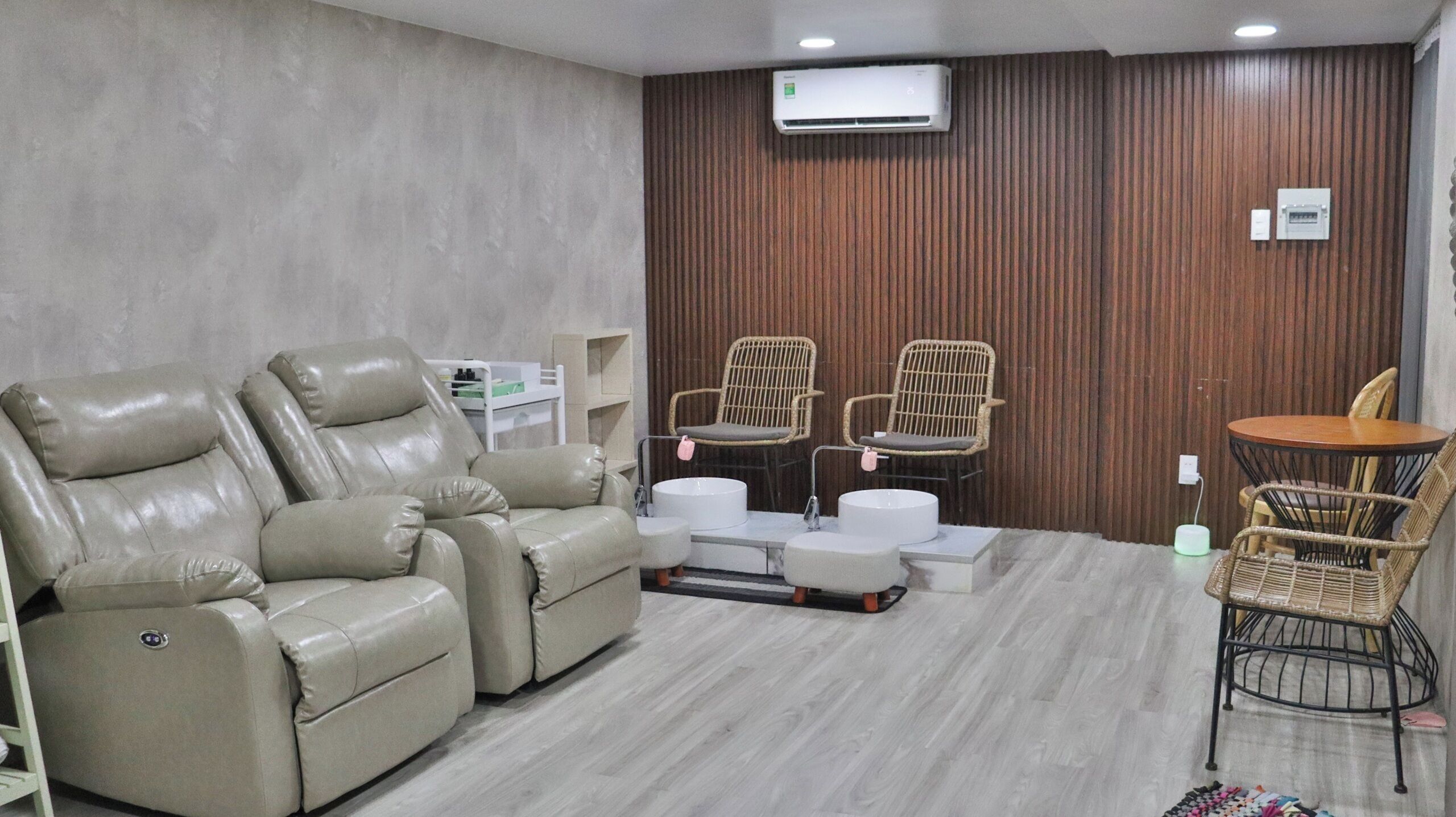 A room with two reclining chairs, a small round table, and two wicker chairs.