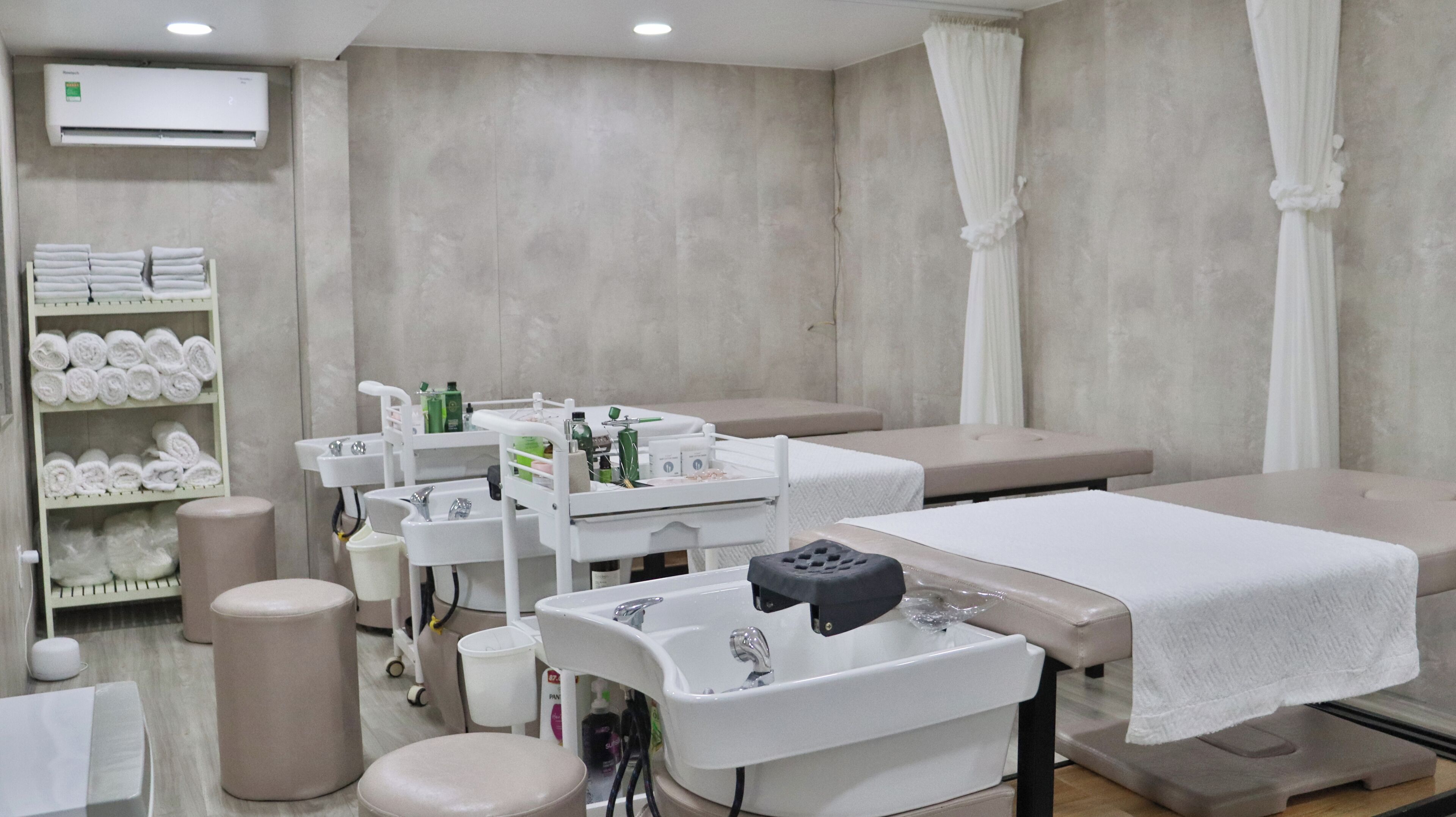 A spa room with a massage table, a sink with toiletries, and a shelf with towels.