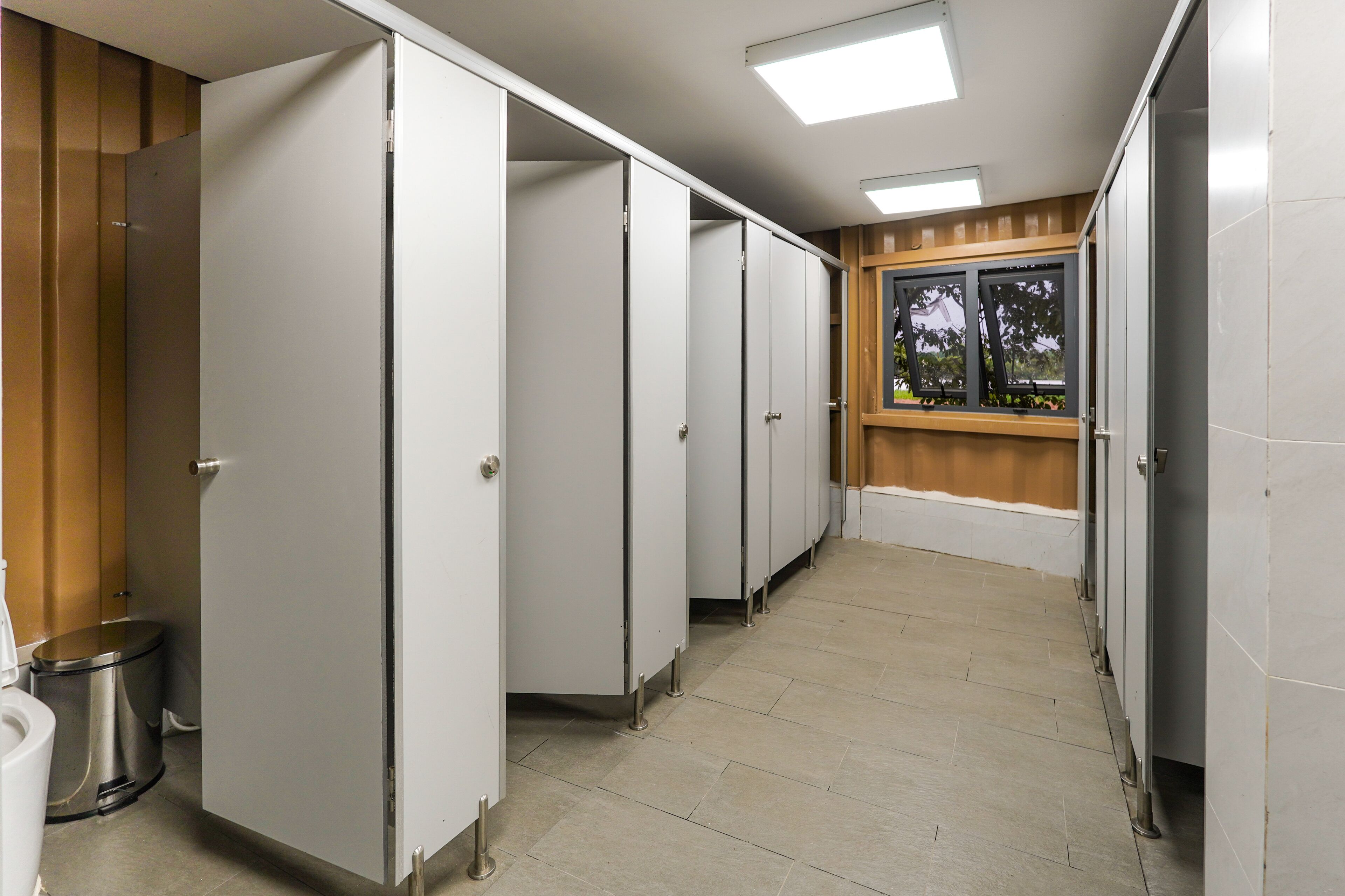 A row of white lockers with a trash can to the left.