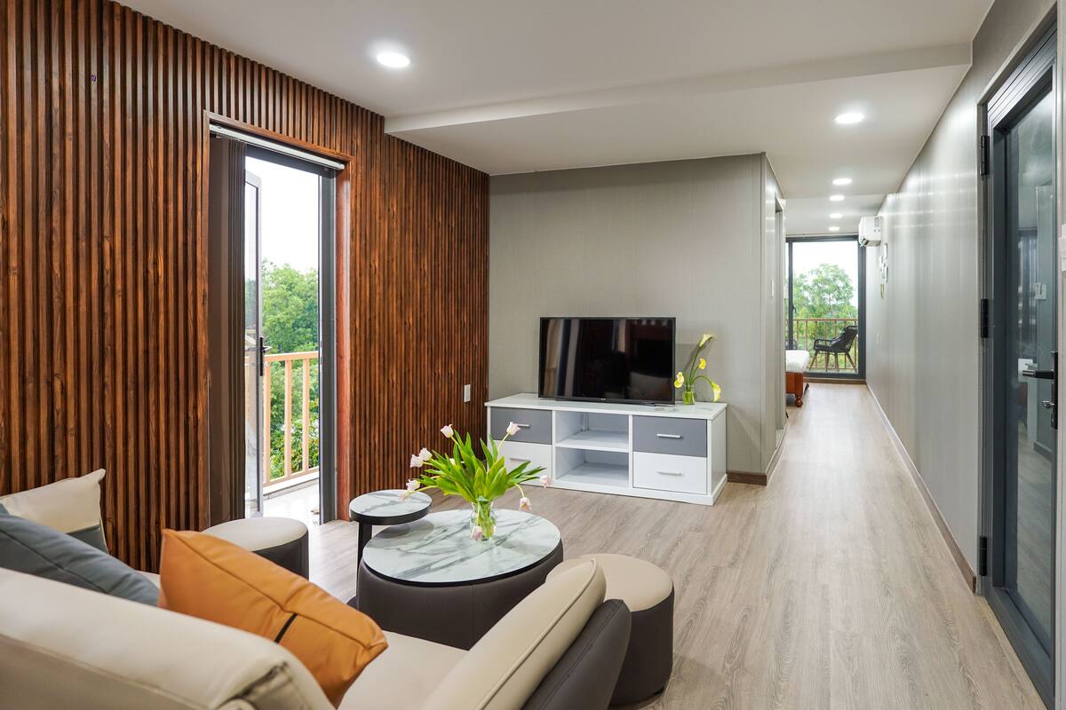 A modern living room with a sofa, a round coffee table, a TV, and a balcony.
