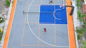 An outdoor basketball court with a blue playing area and orange borders.