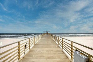 Une promenade en bois qui mène à une plage, avec un ciel dégagé.