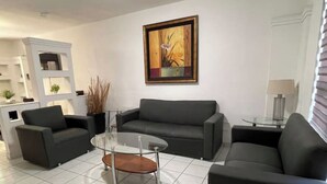 A modern living room with a grey sofa set, a glass coffee table, and a painting on the wall. - House in the Consulate! (Chihuahua)