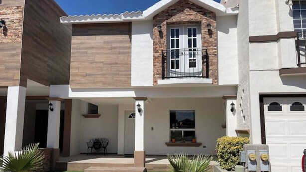 A two-story house with a front porch, a garage, and a small garden with palm trees. - House in the Consulate! (Chihuahua)