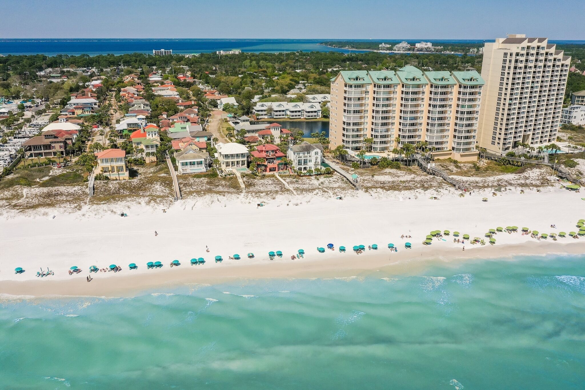 A coastal residential area with beachfront properties, a sandy beach, and a large hotel with multiple floors and balconies.