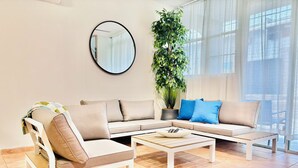 A modern living room with a sectional sofa, a coffee table, a potted plant, and a round mirror on the wall. - Beachside With Private Jacuzzy, Full A/c, Totally Renovated, Brand new (Luquillo)