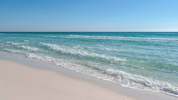 A beach with clear turquoise water and a sandy shore.
