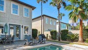 A pool area with lounge chairs, a barbecue grill, and a patio table.