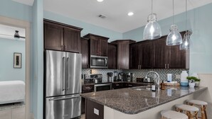 A modern kitchen with dark wood cabinets, stainless steel appliances, and a granite countertop.