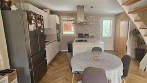 A compact kitchen with a dining table, a refrigerator, and a staircase. - Charming duplex 4 to 6 persons Risoul 1850 (Risoul)